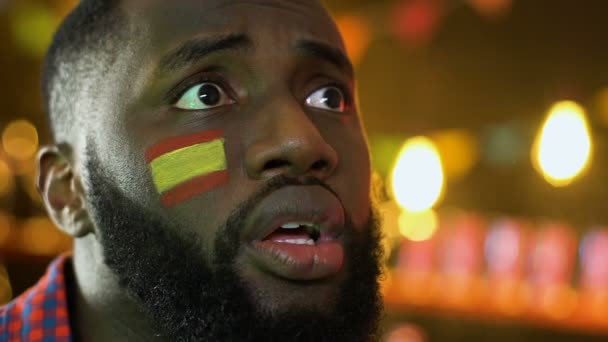 Hombre negro decepcionado viendo el partido de fútbol, bandera española en la mejilla, pérdida — Vídeos de Stock