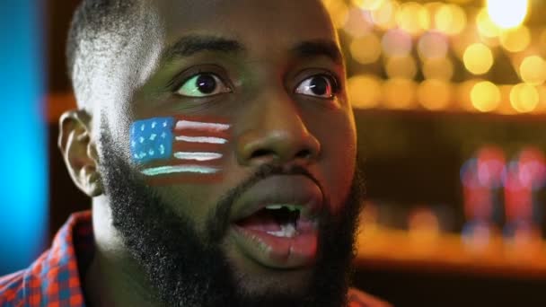 Afro-americký sportovní fanoušek s americkou vlajkou rozčilený o oblíbeném týmu, který ztrácí hru — Stock video