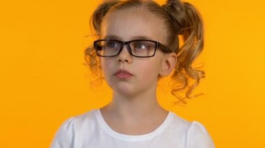 Gözlüklü düşünceli kız öğrenci çenesini kaşıyarak karar vermeye çalışıyor