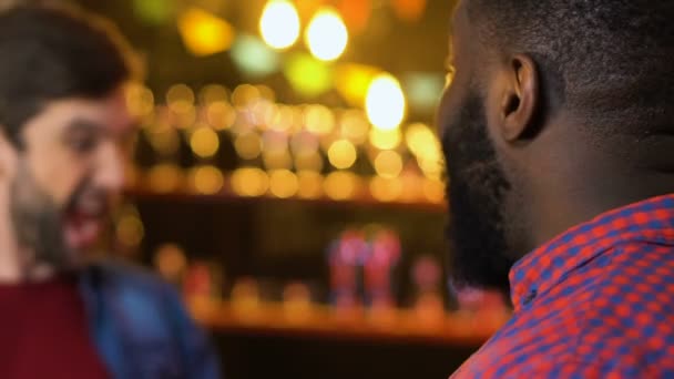 Два мультиэтнических мужчины обнимаются в баре, неожиданные встречи старых друзей, расслабиться — стоковое видео