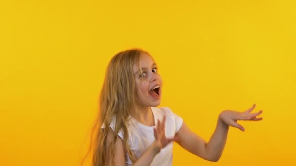 Linda niña de buen humor bailando sobre fondo naranja aislado, cámara lenta — Vídeo de stock