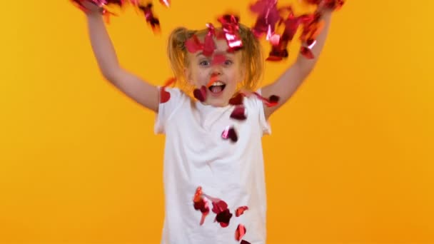 Chica emocionada lanzando confeti en forma de corazón en el aire, fiesta de niños, lento-mo — Vídeos de Stock