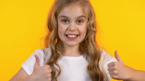 Upphetsad flicka som visar tummen upp och blinkning, framgångsrik lycklig unge på bakgrunden — Stockvideo