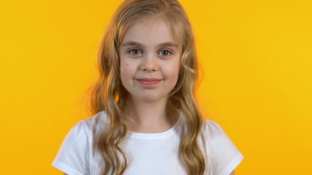 Freundliches Mädchen winkt mit der Hand, freut sich, dich zu sehen, isolierter gelber Hintergrund — Stockvideo