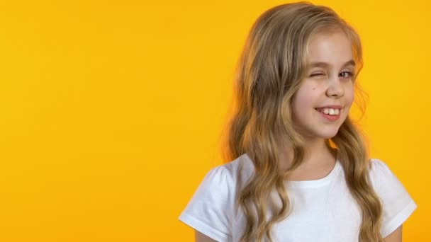 Bella bambina strizzando l'occhio alla fotocamera su sfondo giallo isolato, modello — Video Stock