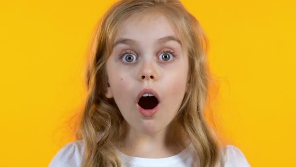 Blonde girl looking extremely shocked hearing news, isolated yellow background — Stock Video