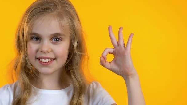 Усміхнена маленька дівчинка показує добре знак і підморгнув, дитина задоволена новою школою — стокове відео