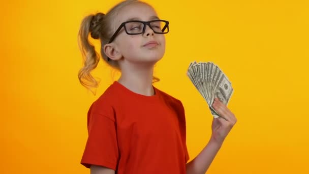 Маленькая умная девочка радуется первым деньгам, размахивает кучей долларов и улыбается — стоковое видео