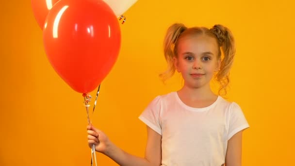 Schattige kleine kind vasthouden gekleurde ballonnen en glimlachend op camera, b-day groet — Stockvideo