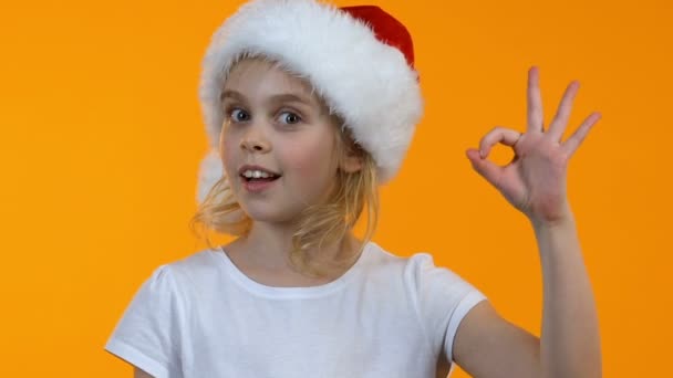 Smiling little santa kid showing ok sign and winking on camera holiday discounts — Stock Video