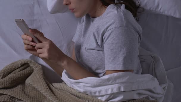 Akıllı telefondan erkek arkadaşıyla sohbet eden, geceleri yatakta yatan, akrabaları olan bir kadın. — Stok video