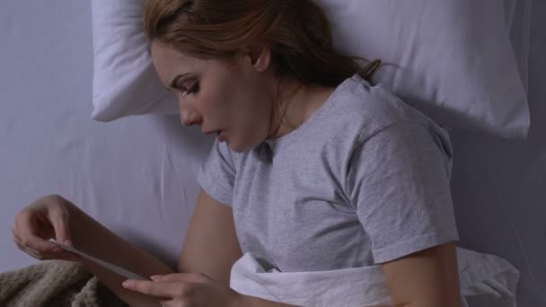 Плачущая молодая вдова лежит в постели, смотрит на фото, пропавший муж, вид сверху — стоковое видео