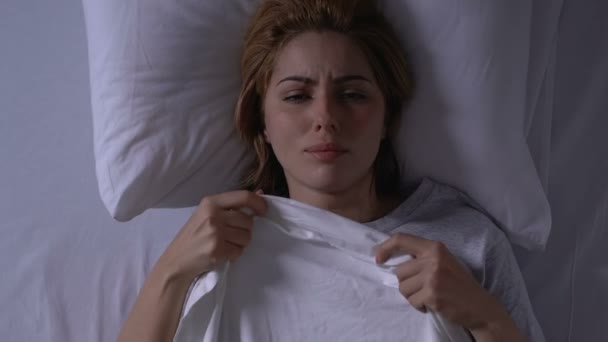 Плачущая женщина лежит в постели, держа одеяло, здоровье и жизненные проблемы, депрессия — стоковое видео