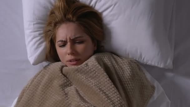 Fiatal beteg nő hidegrázás, takaró az ágyban, influenza tünetek — Stock videók