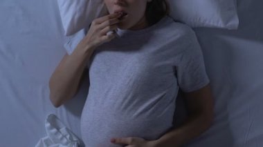 Hamile kadın karın tutan ve yatakta sırt uyku, rahatsız pozisyon