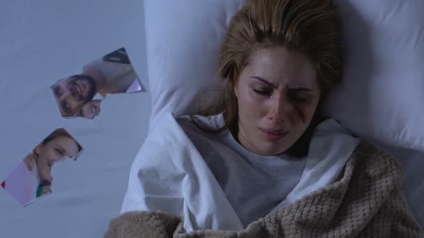 Депрессивная женщина с раненым лицом плачет, порванное фото на кровати, нападение в семье — стоковое видео