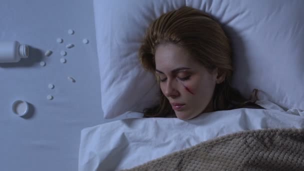 Dame met gewonde gezicht slapen, pillen morsen op bed, problemen na trauma — Stockvideo