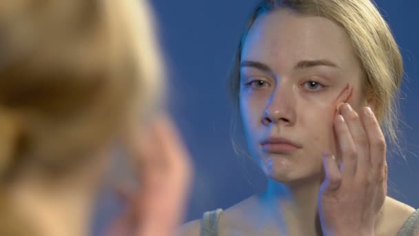 Huilende jonge dame die Foundation Cream toepast op gewond gezicht, het verbergen van geweld — Stockvideo