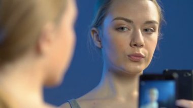 Ayna önünde akıllı telefonda selfie fotoğrafları çeken güzel genç kız