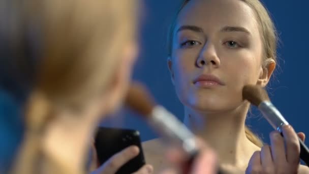 Adolescente femenina viendo lecciones de vídeo de maquillaje en el teléfono inteligente, aplicando polvo — Vídeos de Stock