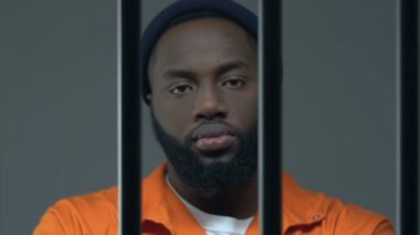 Tehlikeli Afro-Amerikan mahkum adam hapishane barlar aracılığıyla kamera bakıyor