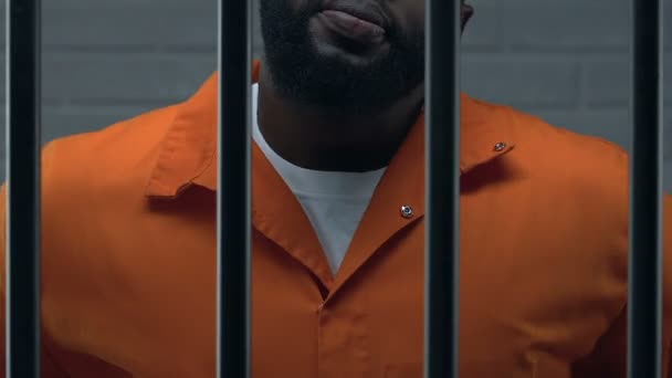 Уверенный афроамериканец глава мафии, стоящий в тюремной камере, преступник — стоковое видео