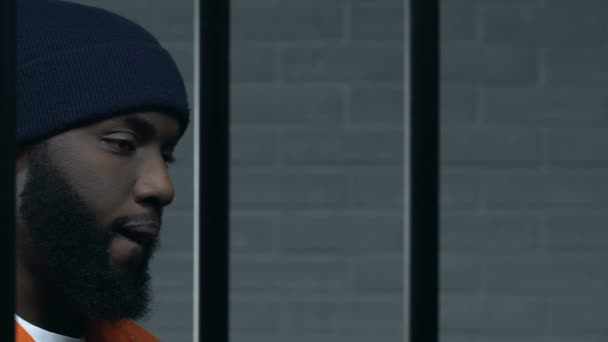 흑인 범죄자는 적극적으로 감옥 바를 들고 카메라를보고, 유죄 — 비디오