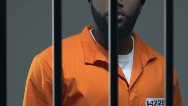 Angry criminoso afro-americano mostrando dedo médio através da cela da prisão, conflito — Vídeo de Stock