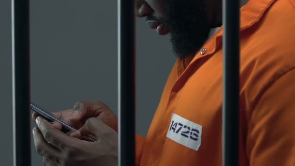 Afro-Amerikaanse gevangene scrollen op smartphone, verboden items in de gevangenis — Stockvideo