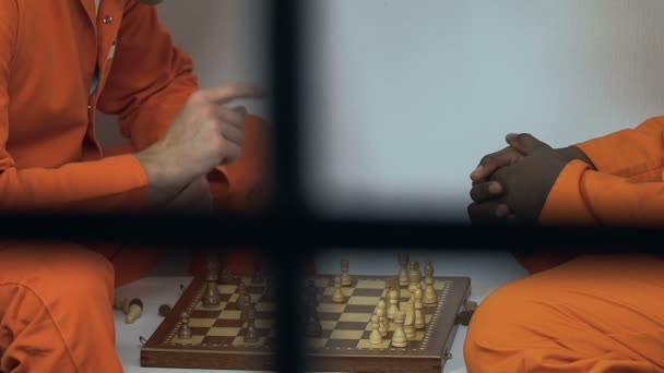Многорасовые сокамерники играют в шахматы в свободное время, тюремные развлечения — стоковое видео