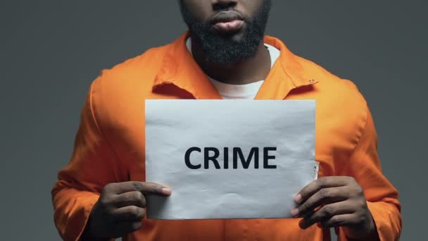 Злочинне слово на картоні в руках чорного в'язня, незаконне покарання — стокове відео