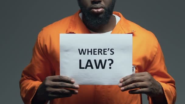 Wheres law question on cardboard in hands of Afro-American prisoner, disorder — Stock Video