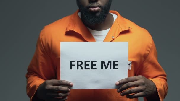 アフロ・アメリカンの囚人の手に段ボールの上に私のフレーズを解放し、恩赦を求める — ストック動画