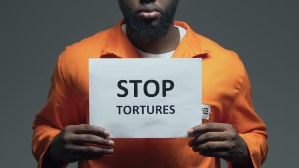 Stoppa tortyr fras på kartong i händerna på Afro-American fånge, misshandel — Stockvideo