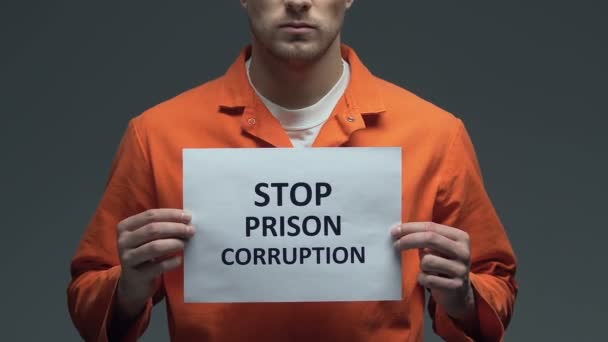 Zatrzymaj zdanie na temat korupcji w więzieniu na tekturze w rękach kaukaskiego więźnia — Wideo stockowe