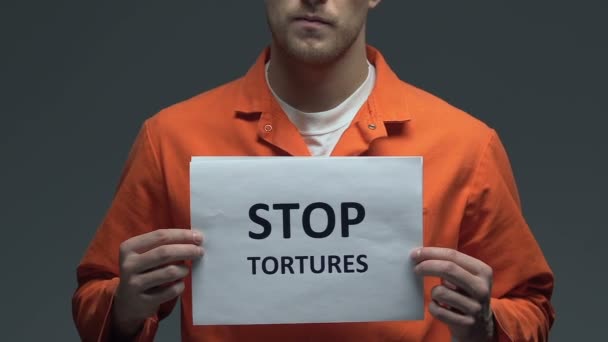 Прекратить пытки фразы на картонке в руках кавказского заключенного, протест — стоковое видео