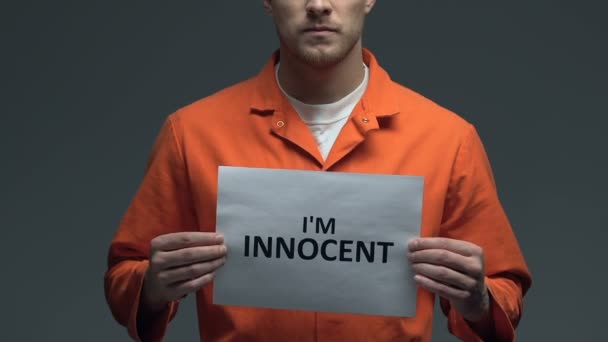 Im frase inocente no cartão em mãos de prisioneiro caucasiano, injustiça criminal — Vídeo de Stock