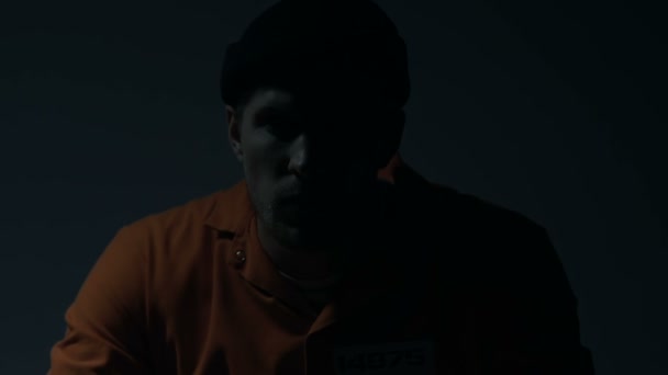 Prisioneiro extremamente perigoso sentado numa cela escura, à espera da pena de morte — Vídeo de Stock