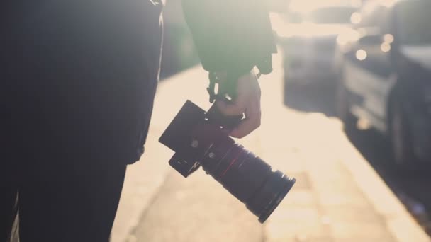 Mężczyzna chodzenie na ulicy trzymając aparat fotograficzny, patrząc pod kątem strzelanie lokalizacja, hobby — Wideo stockowe