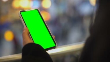 Elinde cep telefonu olan bir kadın, alışveriş merkezinde duruyor, reklam.
