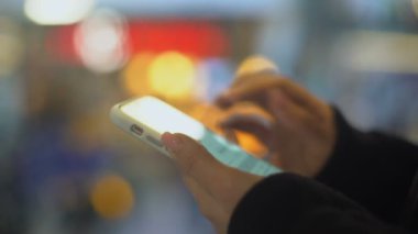 Akıllı telefonları kaydıran genç bir kadın kurye teknolojilerinde arkadaşlarıyla sohbet ediyor.