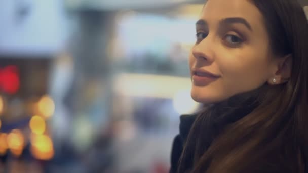 Hermosa joven girando y sonriendo a la cámara, de pie en la estación de tren — Vídeos de Stock