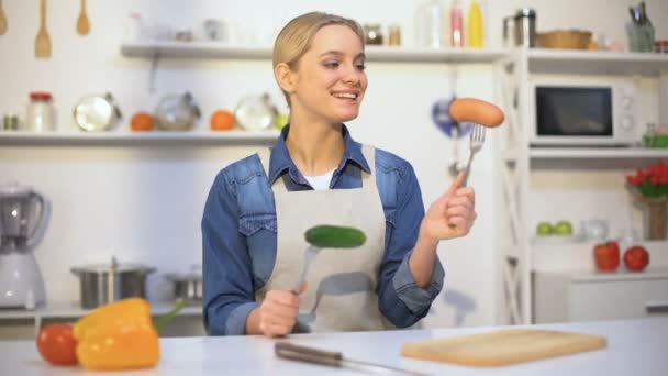 Fille mince au choix entre légumes et saucisses, aliments biologiques vs produits de la gomme — Video