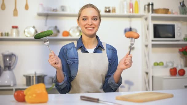 Jolie fille choisissant concombre à la place saucisse, aliments à faible teneur en calories vs glucides — Video