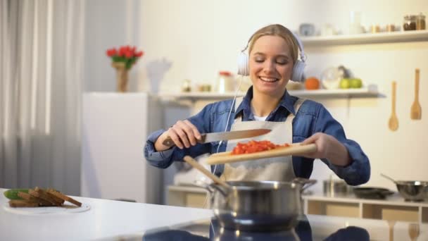 Ragazza positiva ascoltare musica e cucinare verdure, sano consumo a basso contenuto calorico — Video Stock