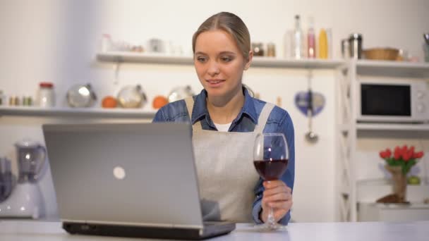 Hermosa mujer bebiendo vino y buscando recetas de comida para una cena romántica — Vídeos de Stock