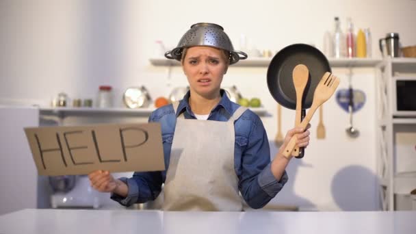 Dona de casa inexperiente pedindo ajuda na cozinha, vestindo panela na cabeça, piada — Vídeo de Stock
