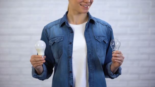 Chica elige bombilla led de ahorro de energía en lugar de lámpara incandescente, eficiencia — Vídeos de Stock