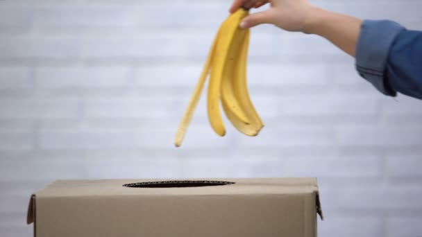 Hand gooien van bananenschil in Prullenbak, recycling Afvalsortering, close-up — Stockvideo