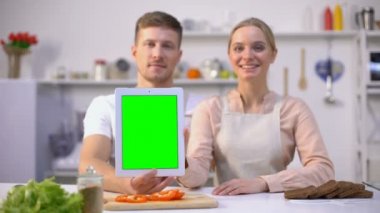 Yeşil ekranlı tablet tutan çift, başparmak ları yukarı ya da lezzetli yemek tarifi uygulaması
